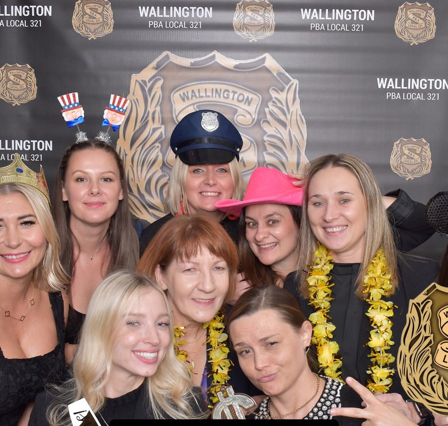 Group posing with props in front of a custom branded step-and-repeat backdrop