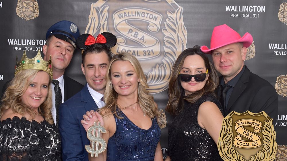 Large group posing at a branded step-and-repeat photo booth backdrop